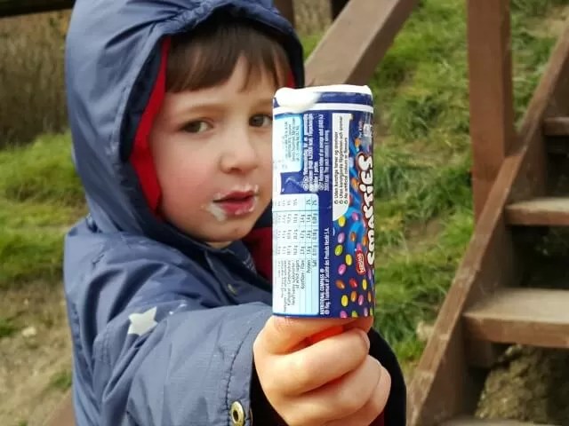 holiding out the empty lollipop wrapper