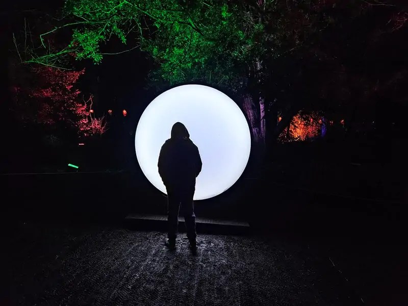 circular white moon light with teen boy stood in shadow in front of it