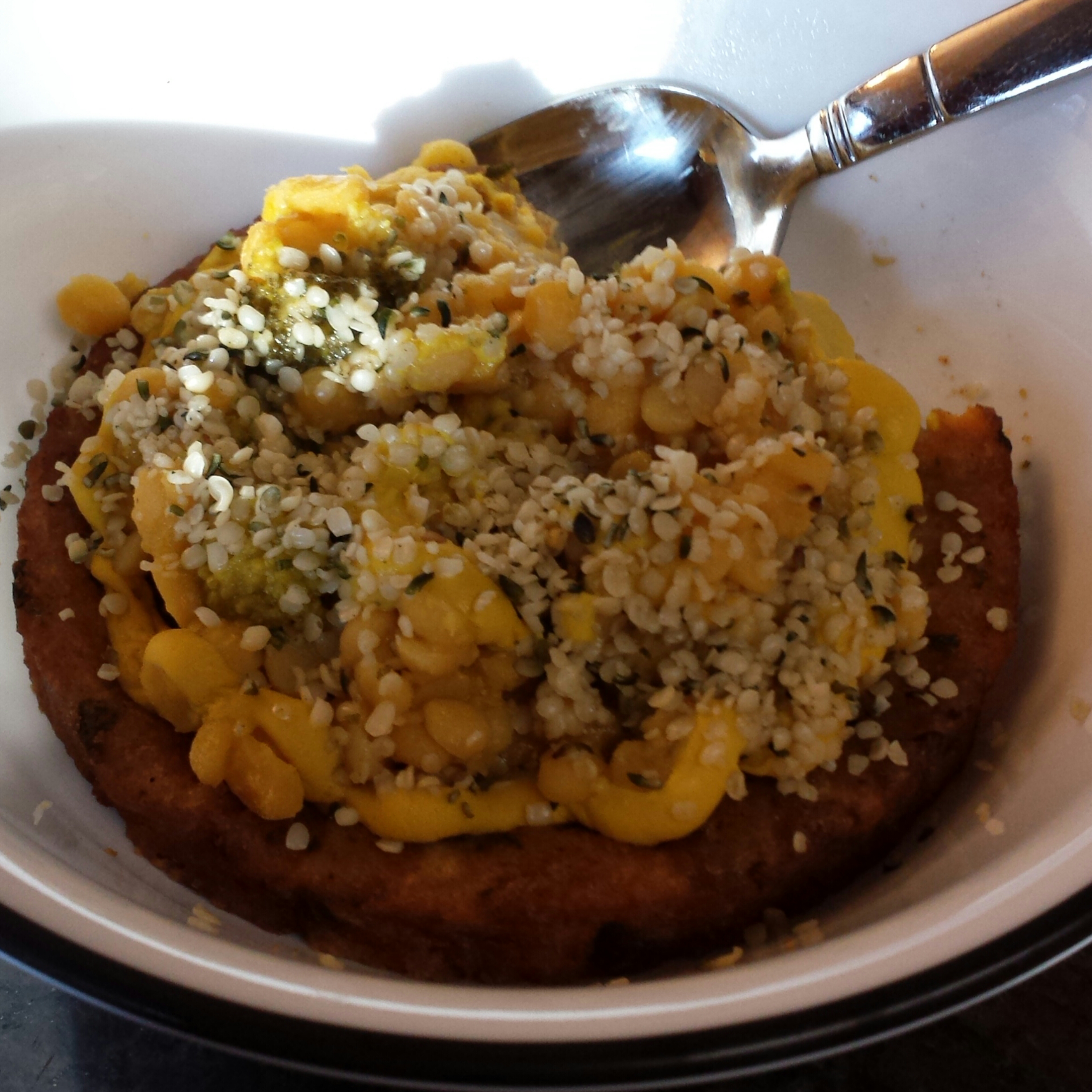 Veggie burger topped with lemony yellow lentils and hemp seeds.