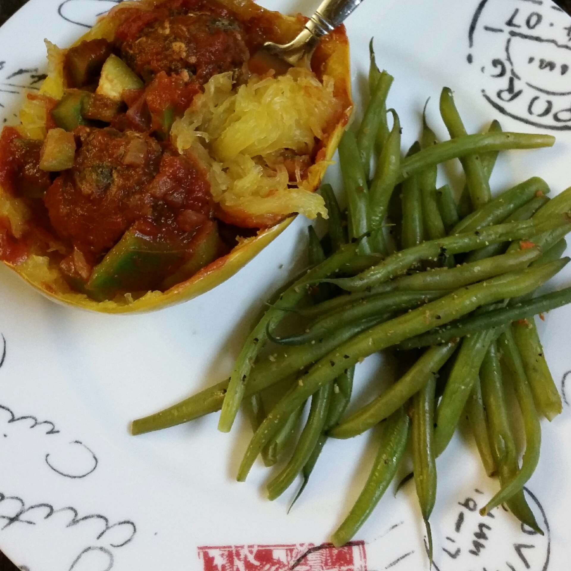 Baked spaghetti squash bowls with vegan neatballs and sweet pepper and onion pasta sauce with a side of steamed green beans