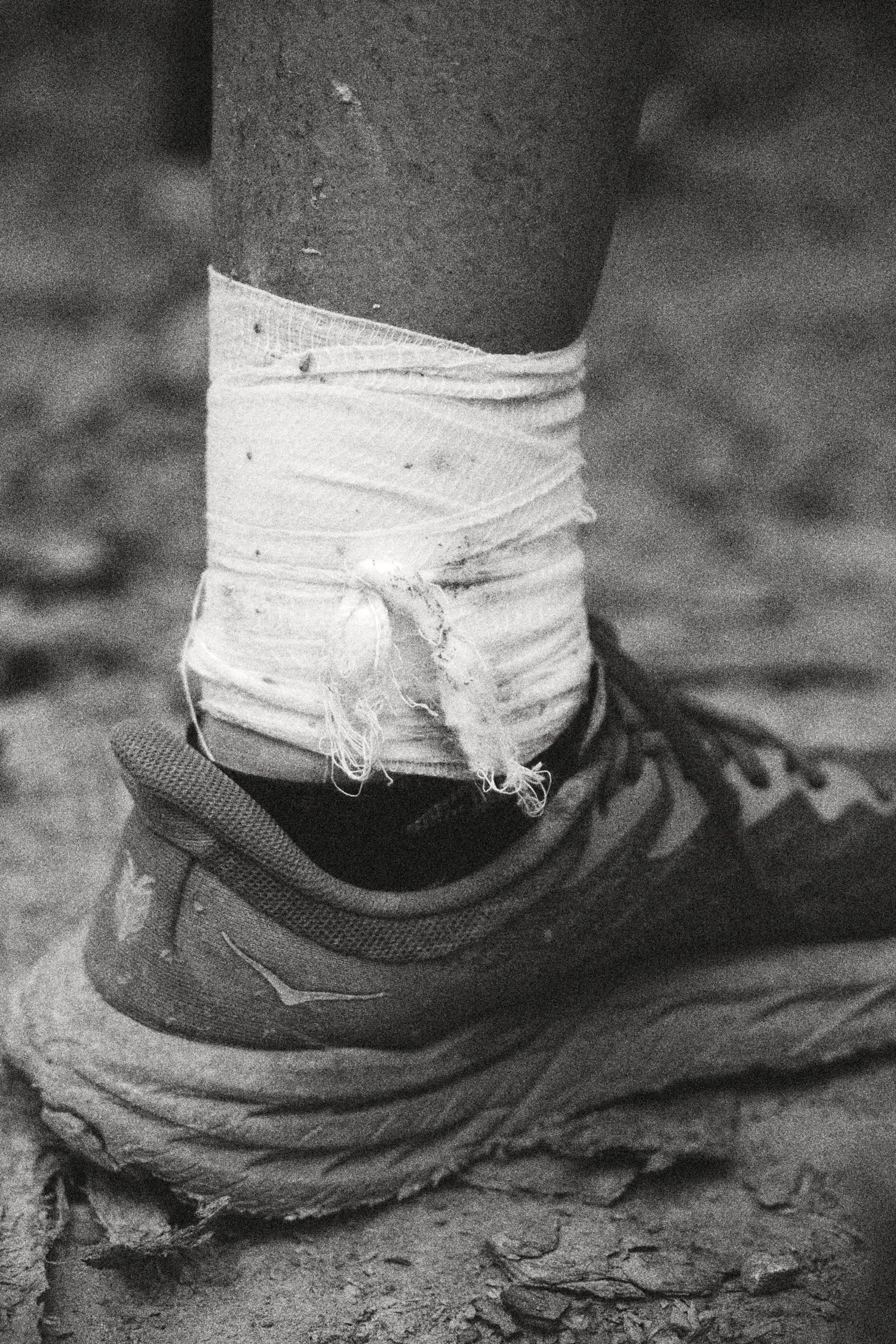 Zdjęcie przedstawia sportowe buty i bandaż na nodze, symbolizujące wysiłek i wytrzymałość w treningu.