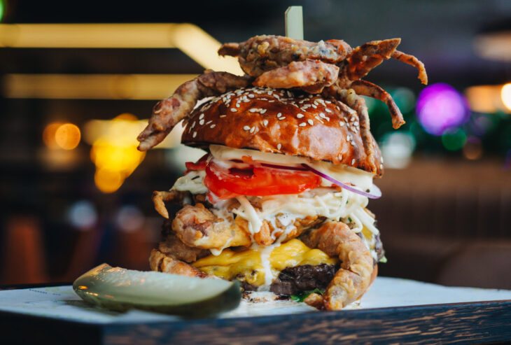 Giant burger with seafood crab shrimps cheese in cafe.