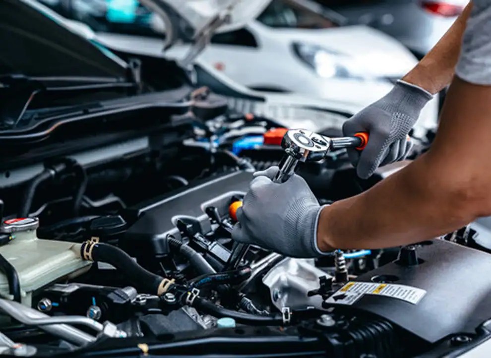 Gloved technician using a ratchet while working on an engine.