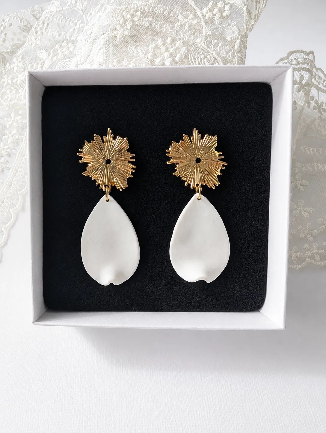 Les boucles d’oreilles Zélie associent une puce dorée en forme de soleil à un délicat pétale blanc façonné à la main en porcelaine froide. Une création élégante et légère, idéale pour accompagner une tenue de mariée ou apporter une touche raffinée à une tenue du quotidien.