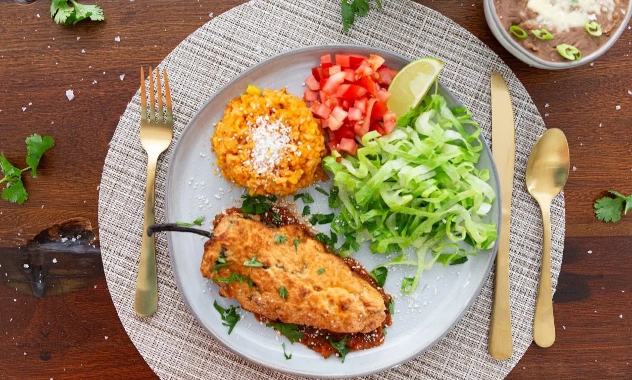 Amazing Crispy Battered Air Fryer Chile Rellenos Recipe- Gluten Free plated with refried beans, spanish rice, lettuce, and tomatoes