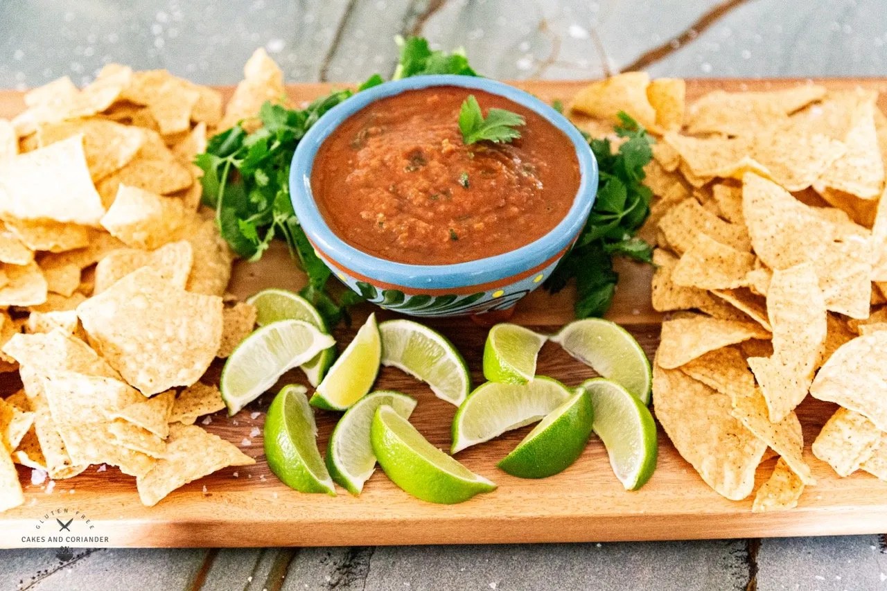 front view of board with restaurant style salsa with tortilla chips and limes