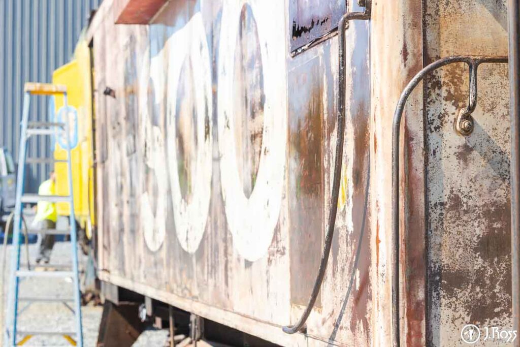 Side view of rusted brown caboose with faded SOO Line lettering before repainting at J. Ross Painting & Drywall