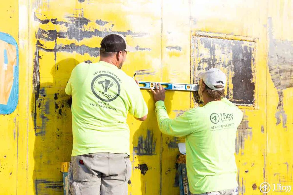 J. Ross crew using a level to mark out the white stripe on the caboose before painting