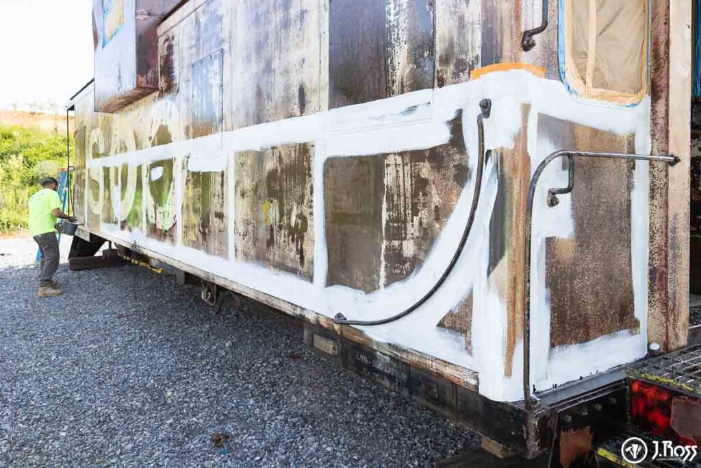 Close-up of brush and roller application on the caboose’s lower panels