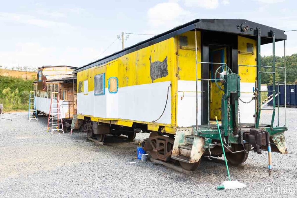 Side view of the cabooses mid-restoration with fresh white stripe and taped windows