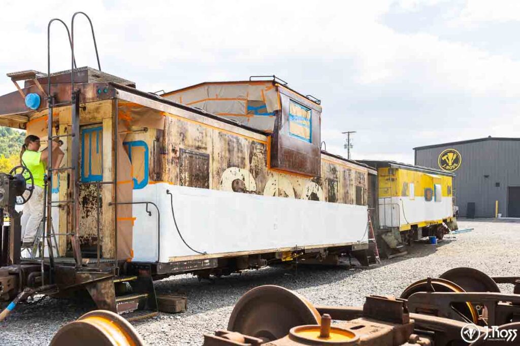 Restoration in progress on historic SOO Line caboose with white Sher-Cryl stripe freshly applied by J. Ross Painting & Drywall