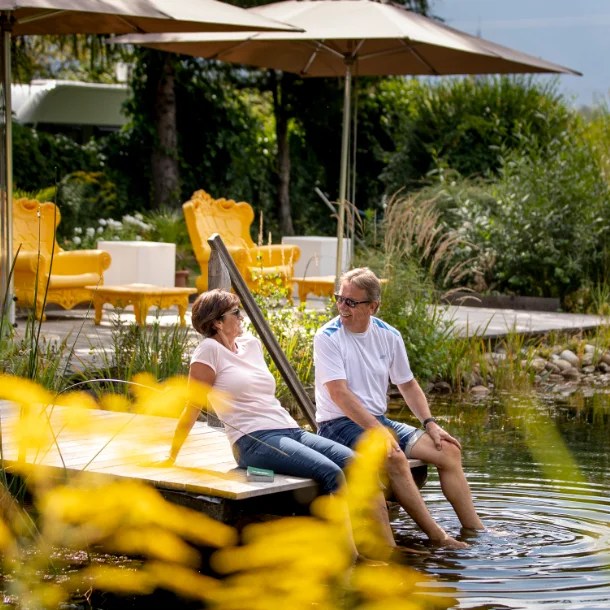 2 Personen sitzen gemütlich am Schwimmteich des 50 plus Campingpark Fisching