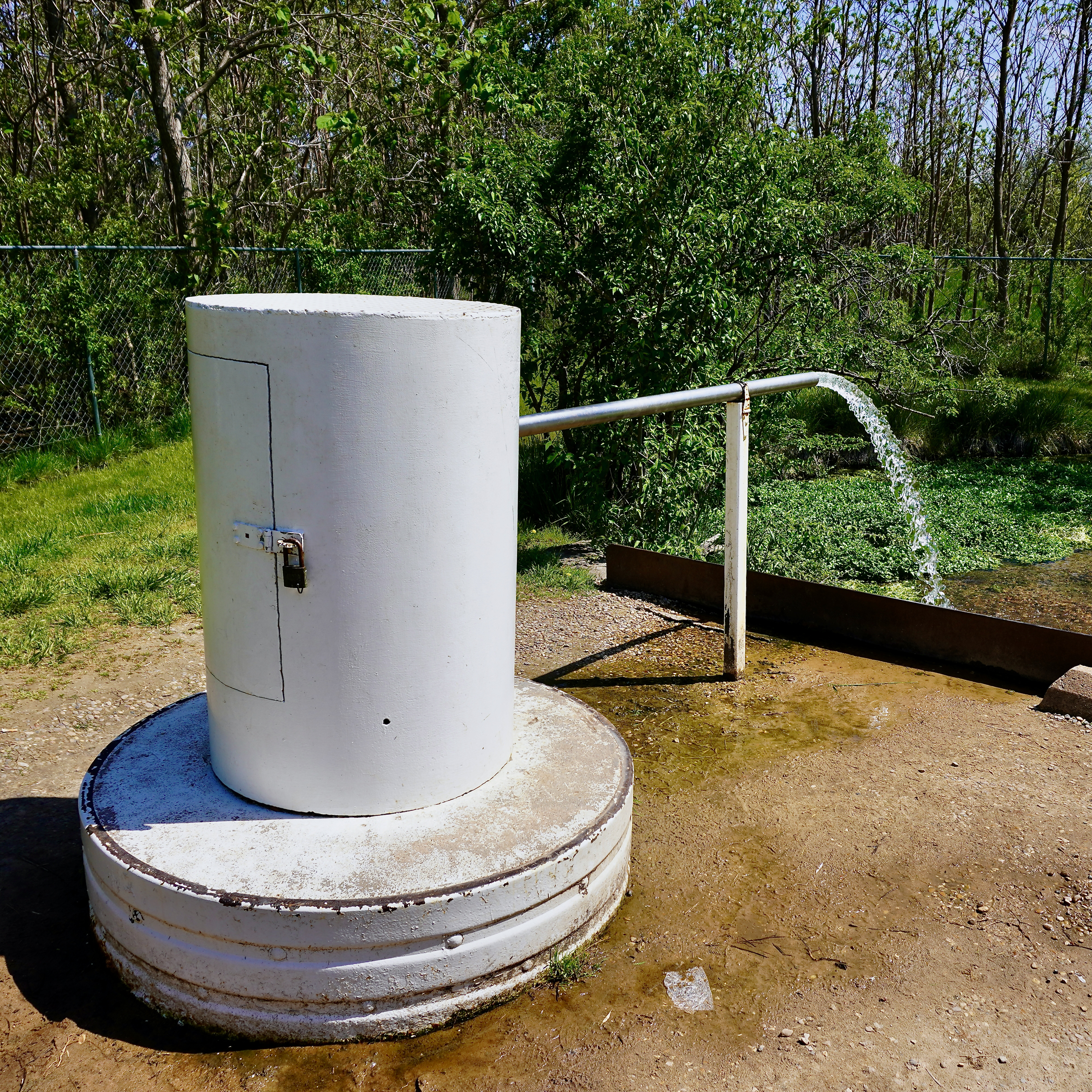 a white cylinder with a pipe of water spraying out from the tapped spring
