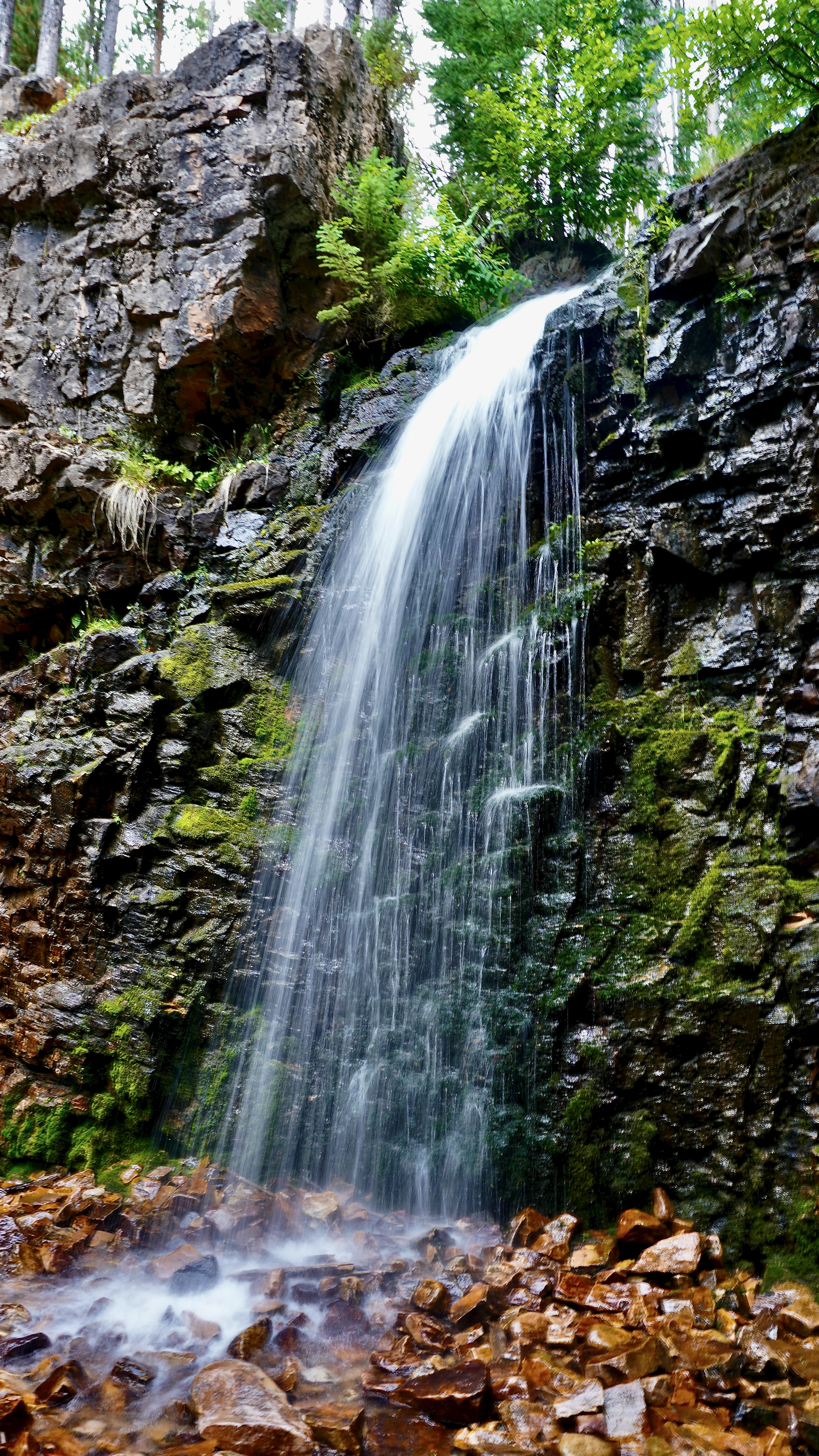 a stone wall with water falling off of it at lower memorial falls montana