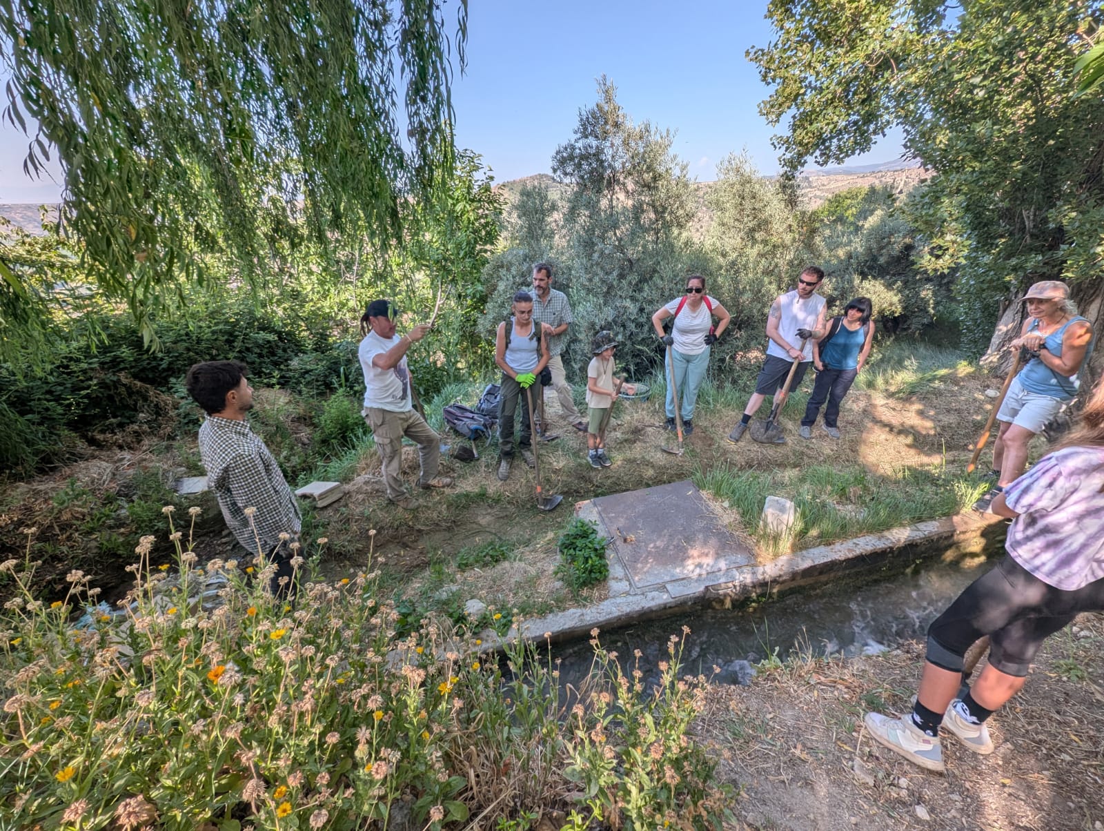 Voluntariado ambiental limpiando una acequia histórica en un entorno rural para conservar patrimonio hidráulico -1