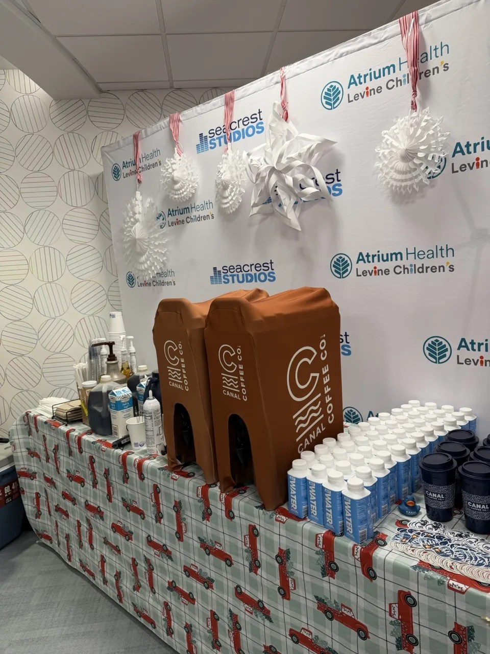 Canal Coffee beverage station with dispensers, bottled water, and branded cups at an Atrium Health event.