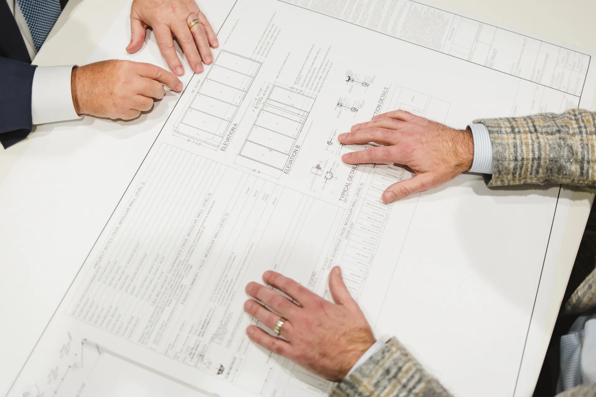 Two professionals reviewing commercial office design plans during a collaborative workspace planning session.