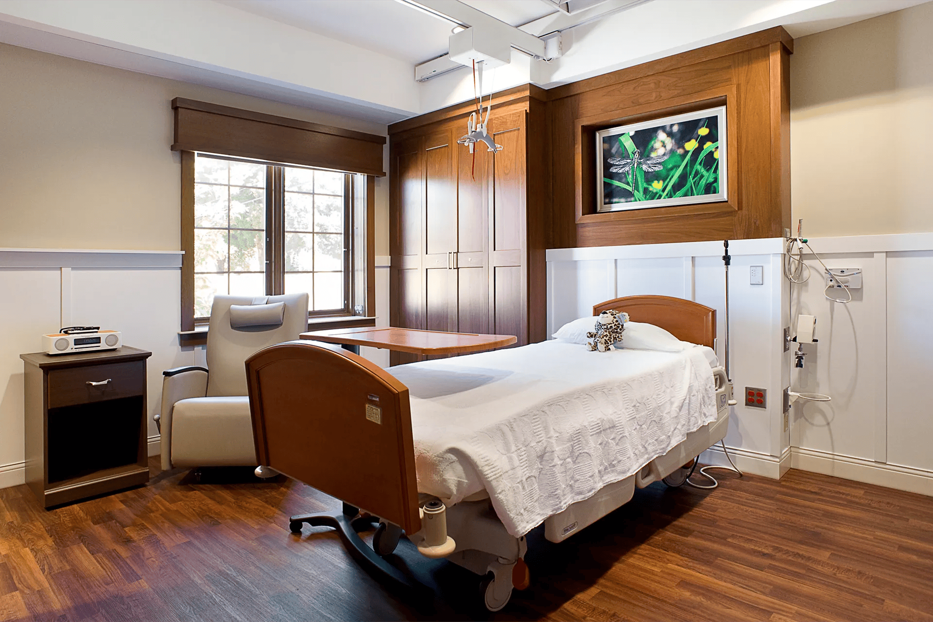 A calming healthcare patient room with a hospital bed, wooden cabinetry, and natural light, designed for patient comfort and recovery.