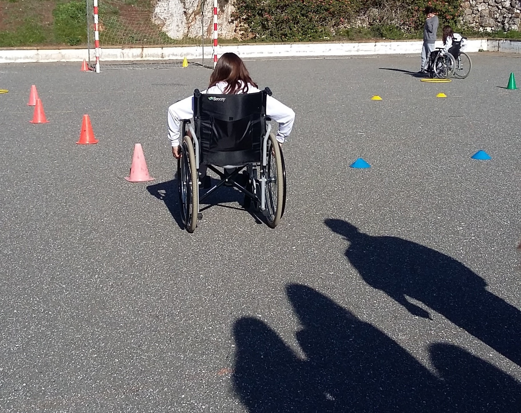 Aluna em cadeira de rodas com silhuetas de pessoas atrás