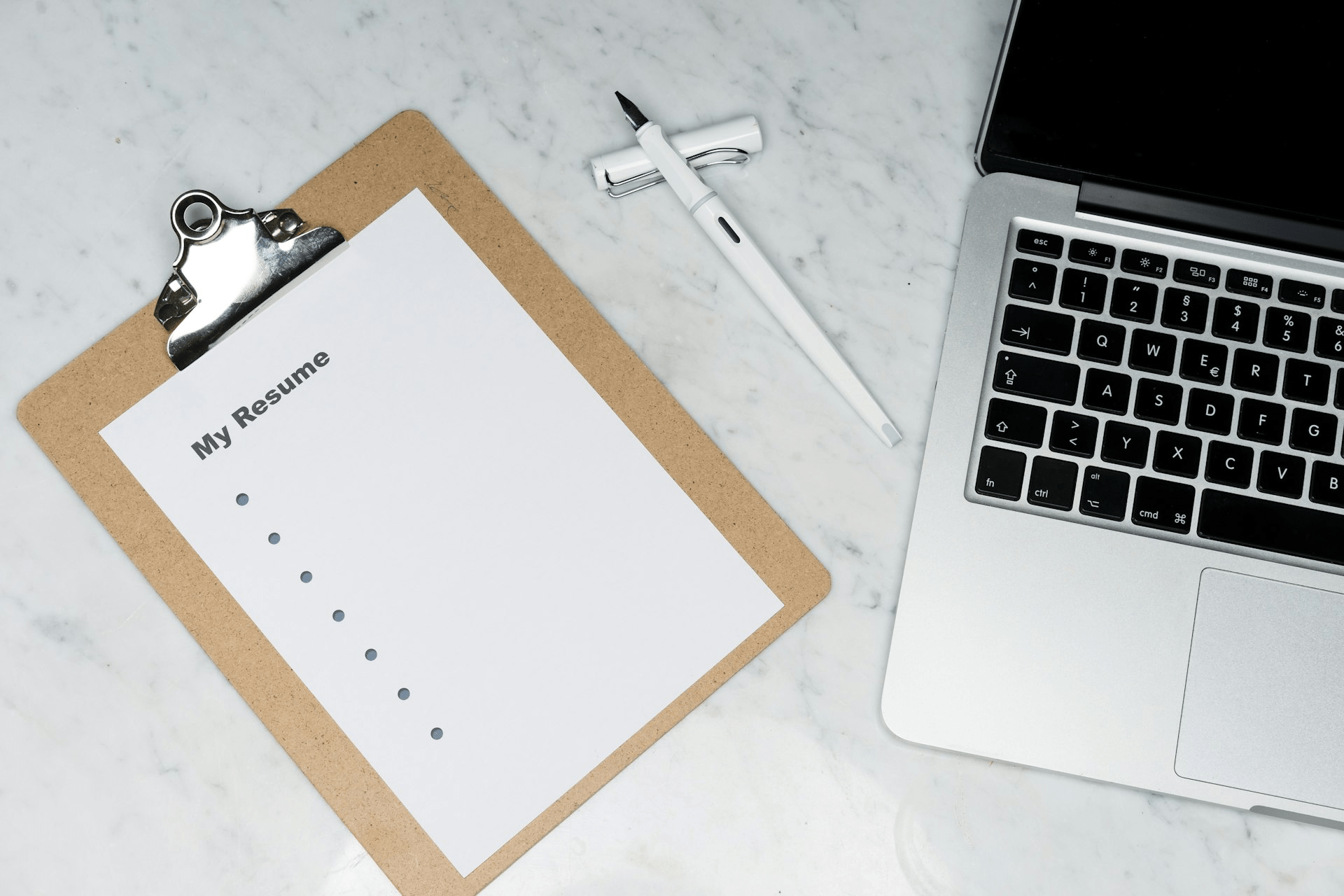 Printed resume documents beside an open laptop on a desk