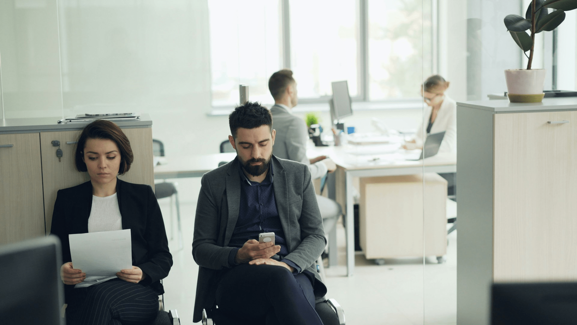 Two people waiting in an office lobby before a meeting