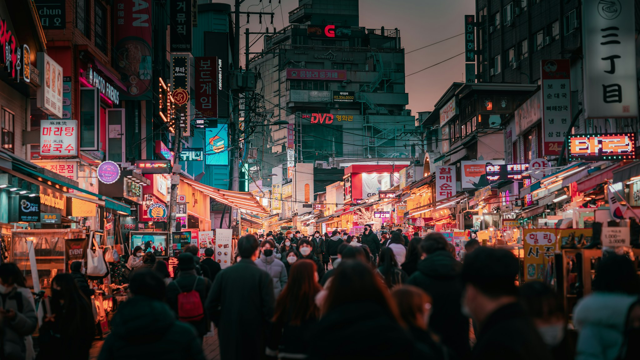 A crowd of people walking along a Seoul street beside tall buildings