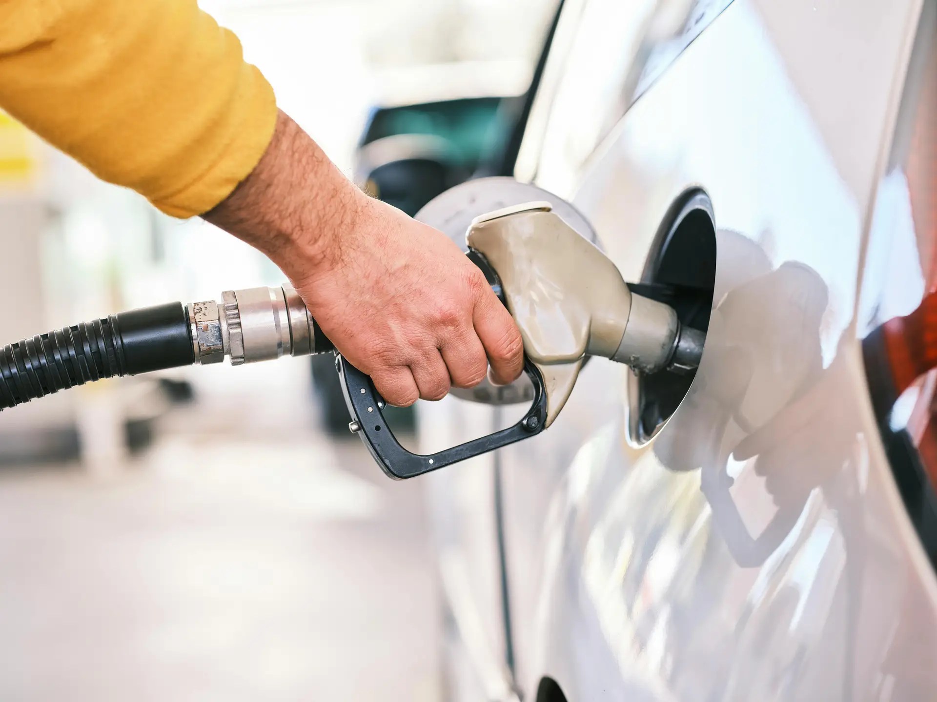 "Man refueling car at gas station showing how to get better mileage and improve fuel efficiency"