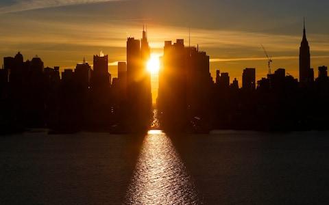 The sun rises over 42nd Street next to the Empire State Building as seen from Weehawken, New Jersey, US.