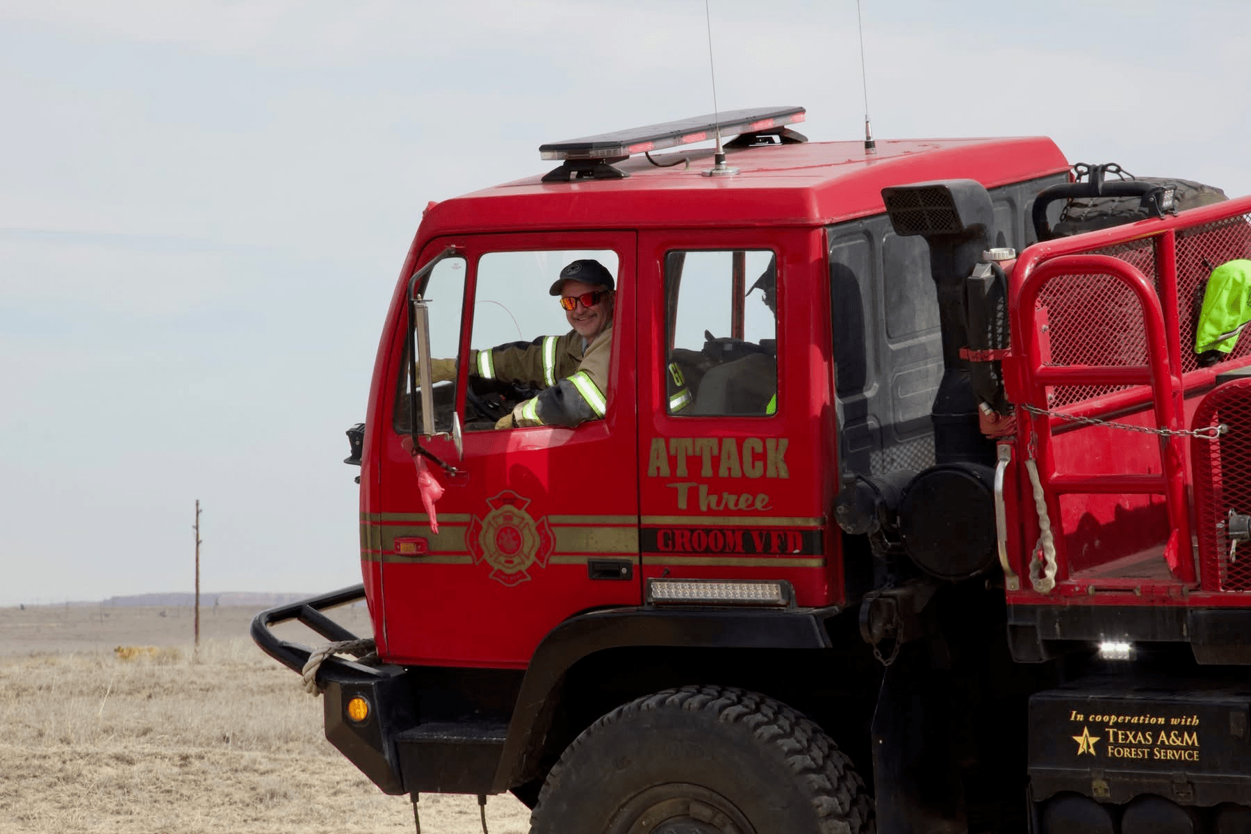 A Fire Fighter driving a Fire Truck in a field.