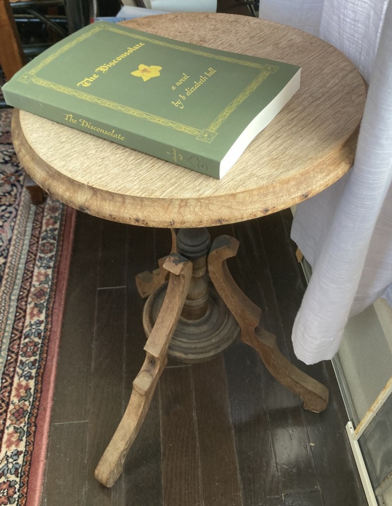 a green book with yellow letters on an old round table with a white curtain