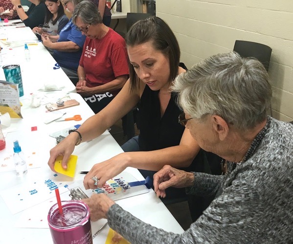Young woman helping her grandmother during craft class