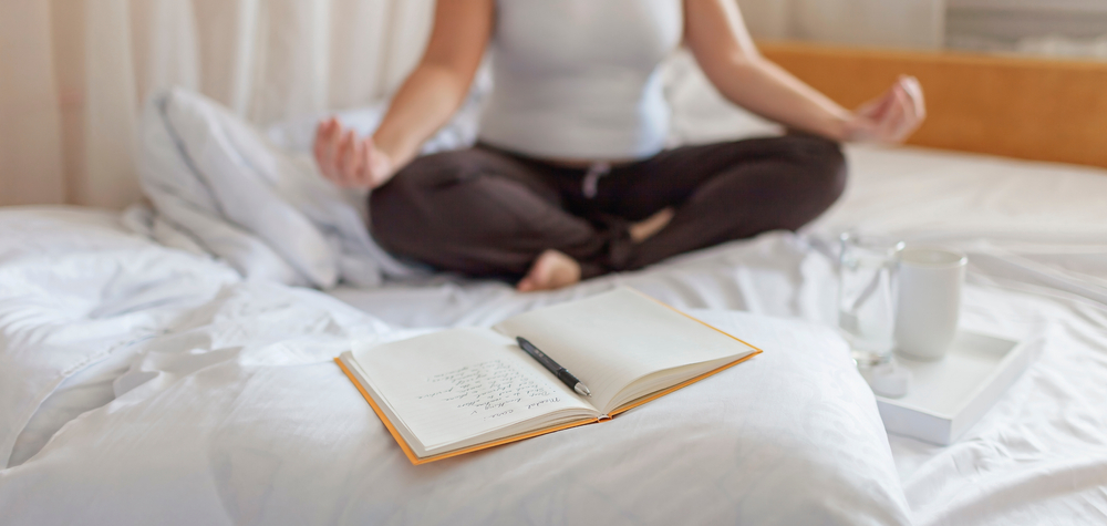 woman on bed with diary and pen nearby