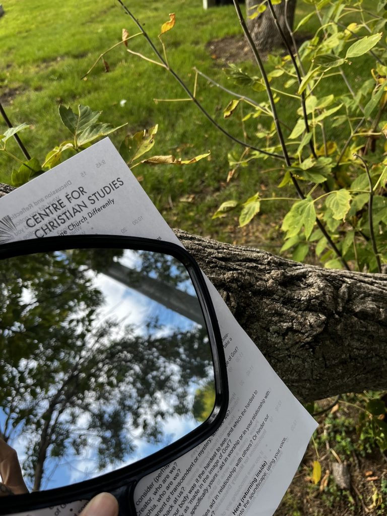 a hand mirror reflecting the sky and a page of instructions for a reflective activity