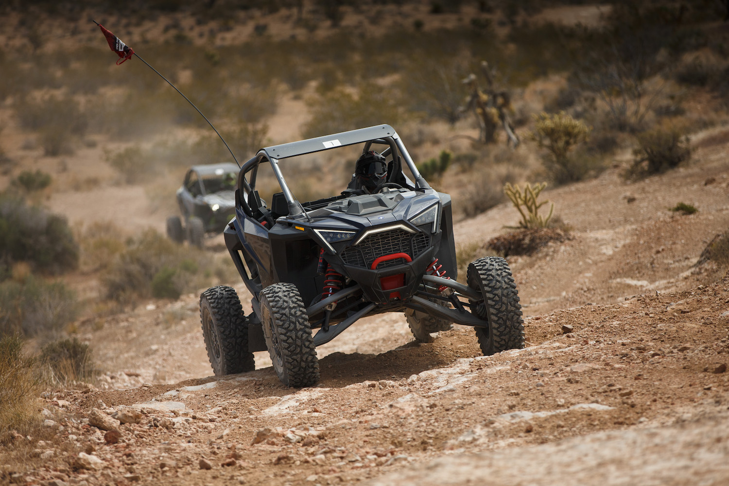 Close up of Polaris RZR Pro R front end on a dirt trail going up a hill in the desert.