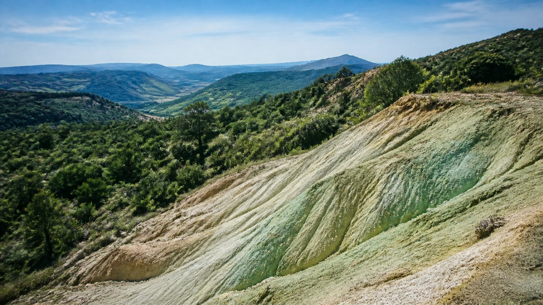 Panoramic view of a sun-drenched French hillside where green clay is sourced