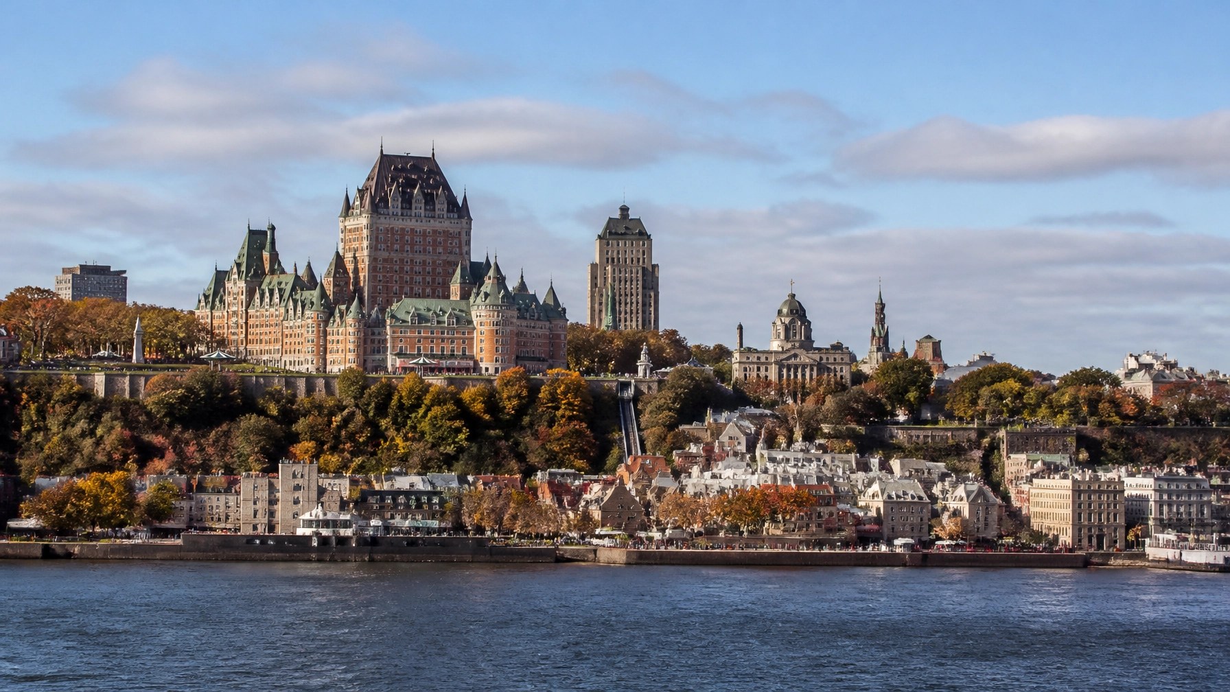 Elegant cruise ship approaching Quebec City with crimson and gold autumn forests along the shoreline
