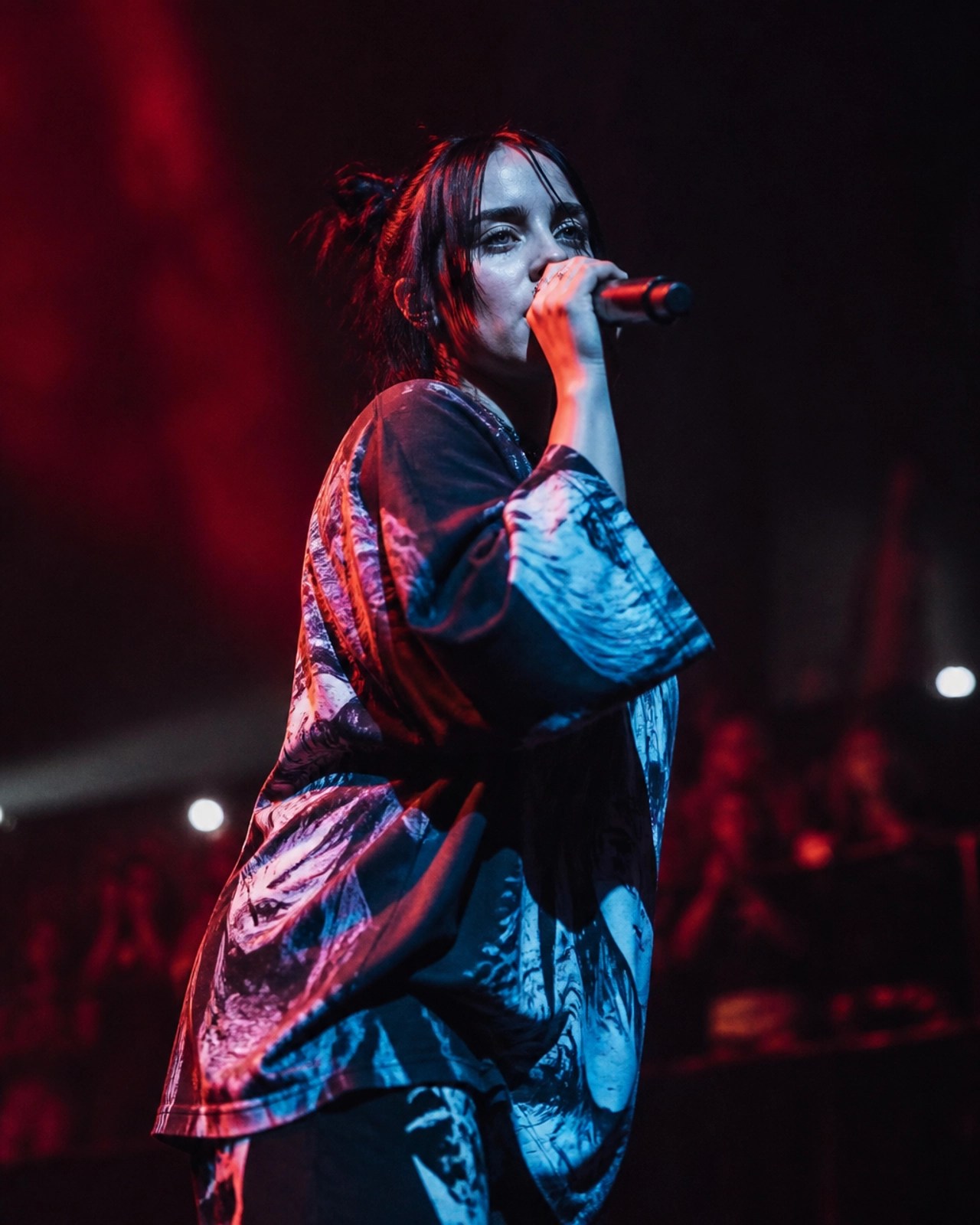 An artist performing on a dark stage with moody red and blue lighting