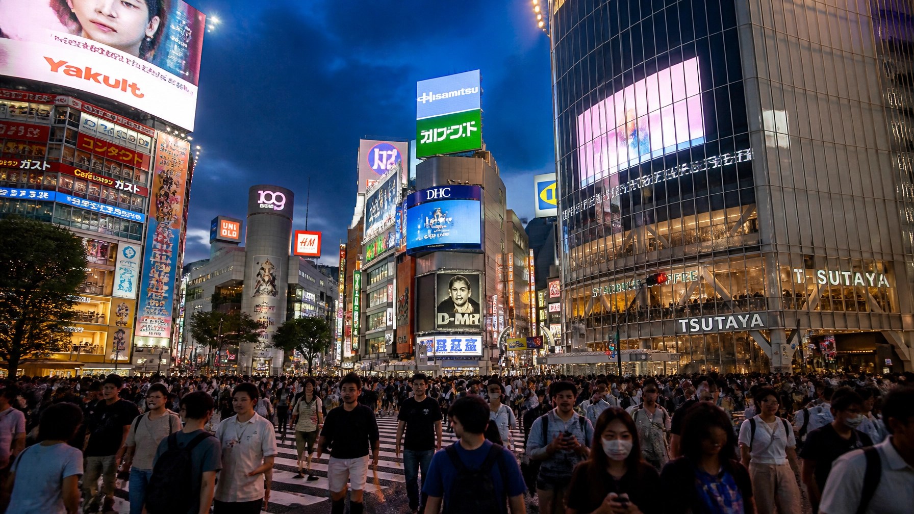 A sea of people crossing Shibuya Crossing under massive digital billboards in Tokyo