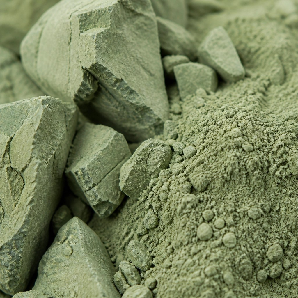 Macro shot of fine, earthy green clay particles highlighting its mineral texture