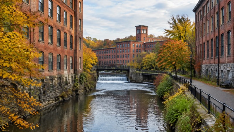 Historic brick mill district streetscape beside Browns Race in autumn