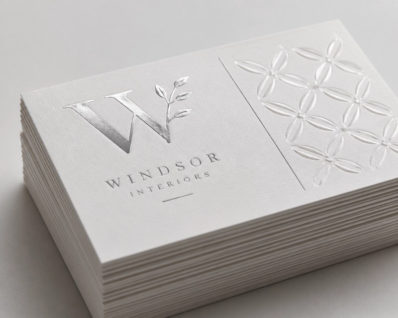 Premium white cardstock featuring silver foil and raised UV finishes for high-impact business collateral.