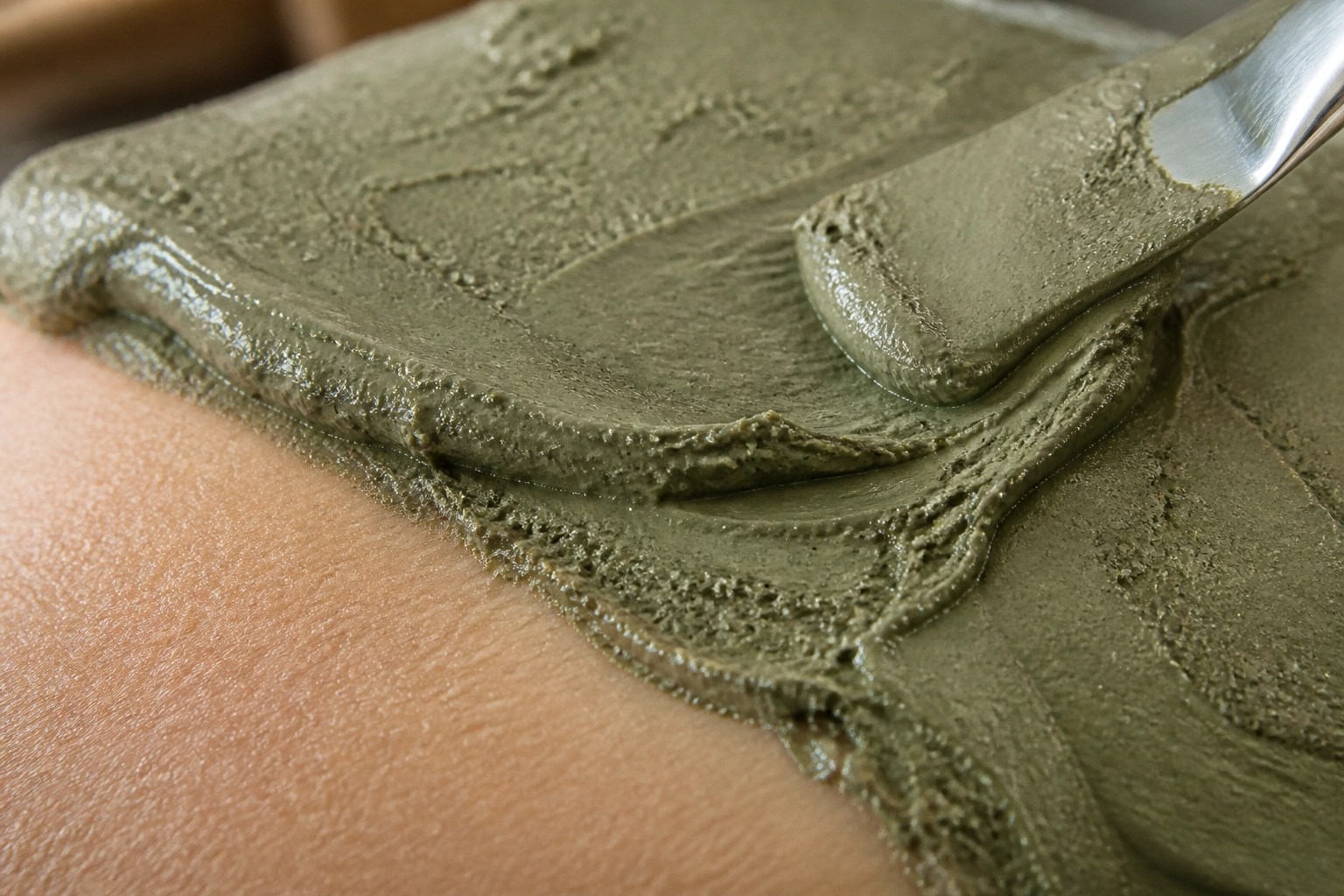 Macro shot of textured French green clay on skin for pore detoxification and healing.