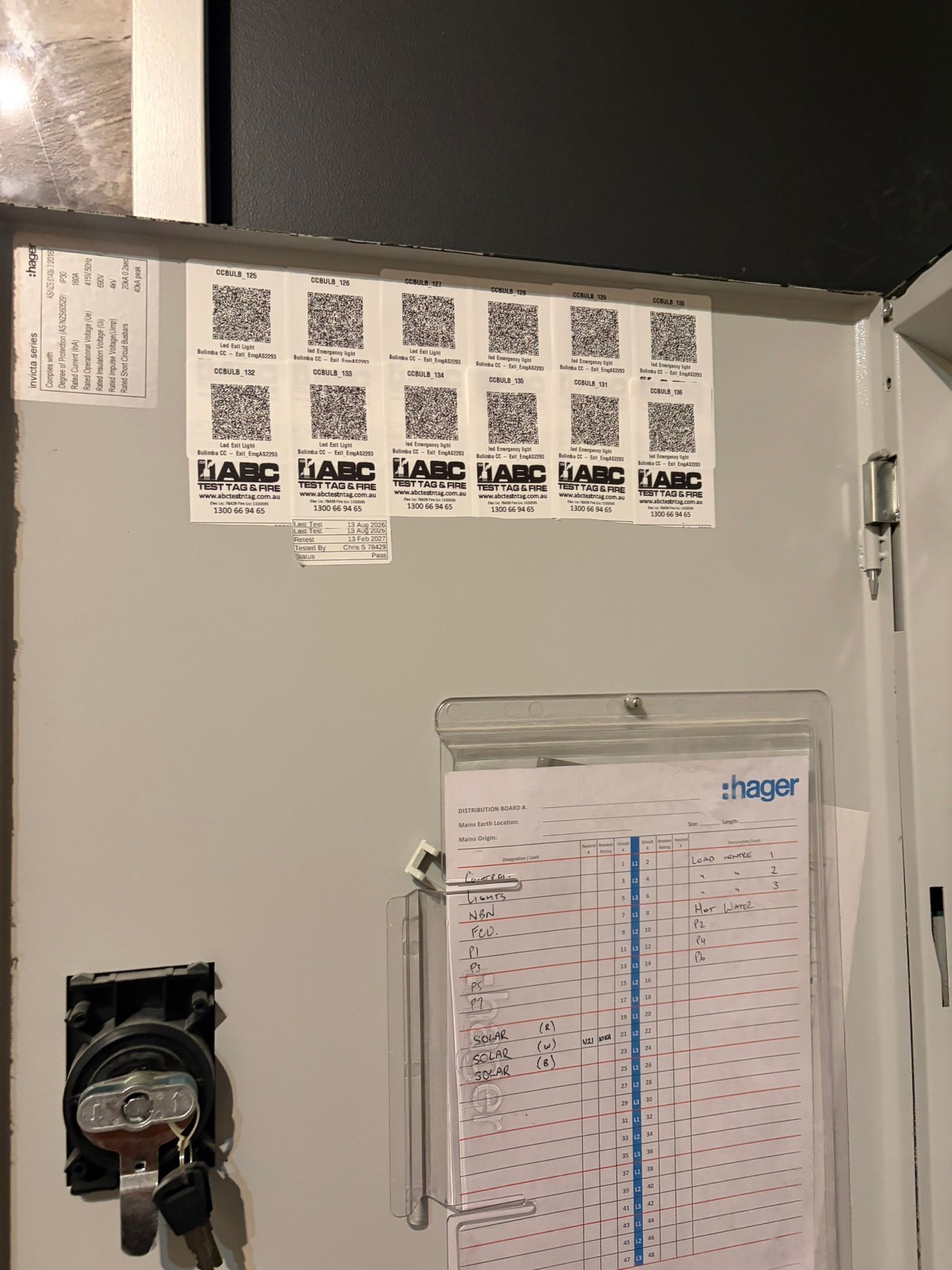 QR-coded compliance labels installed on a distribution board during electrical safety compliance testing