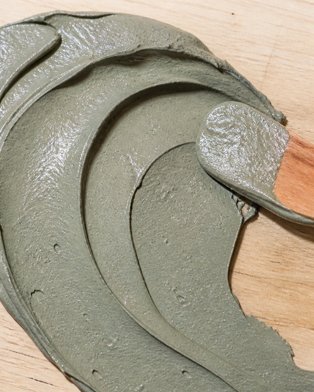 Close-up of rich, textured green clay being spread on a surface