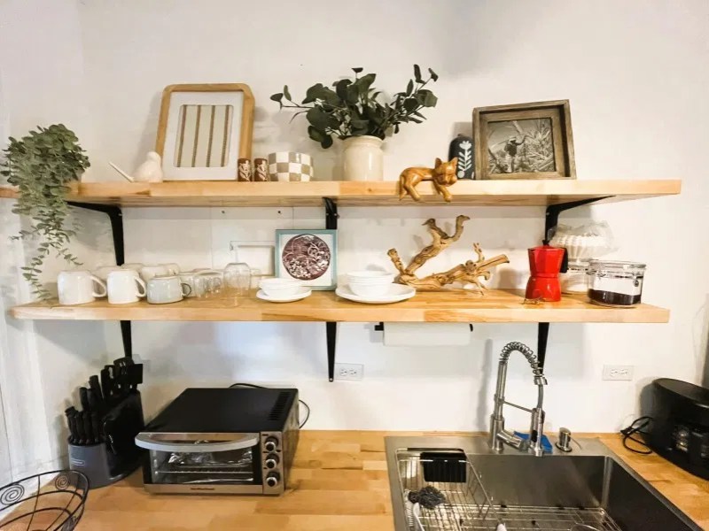 Light wood open kitchen shelving with mugs and coffee supplies in a vacation rental
