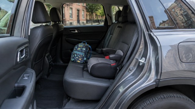 Illustrative view of a child’s booster seat and backpack inside a stationary vehicle