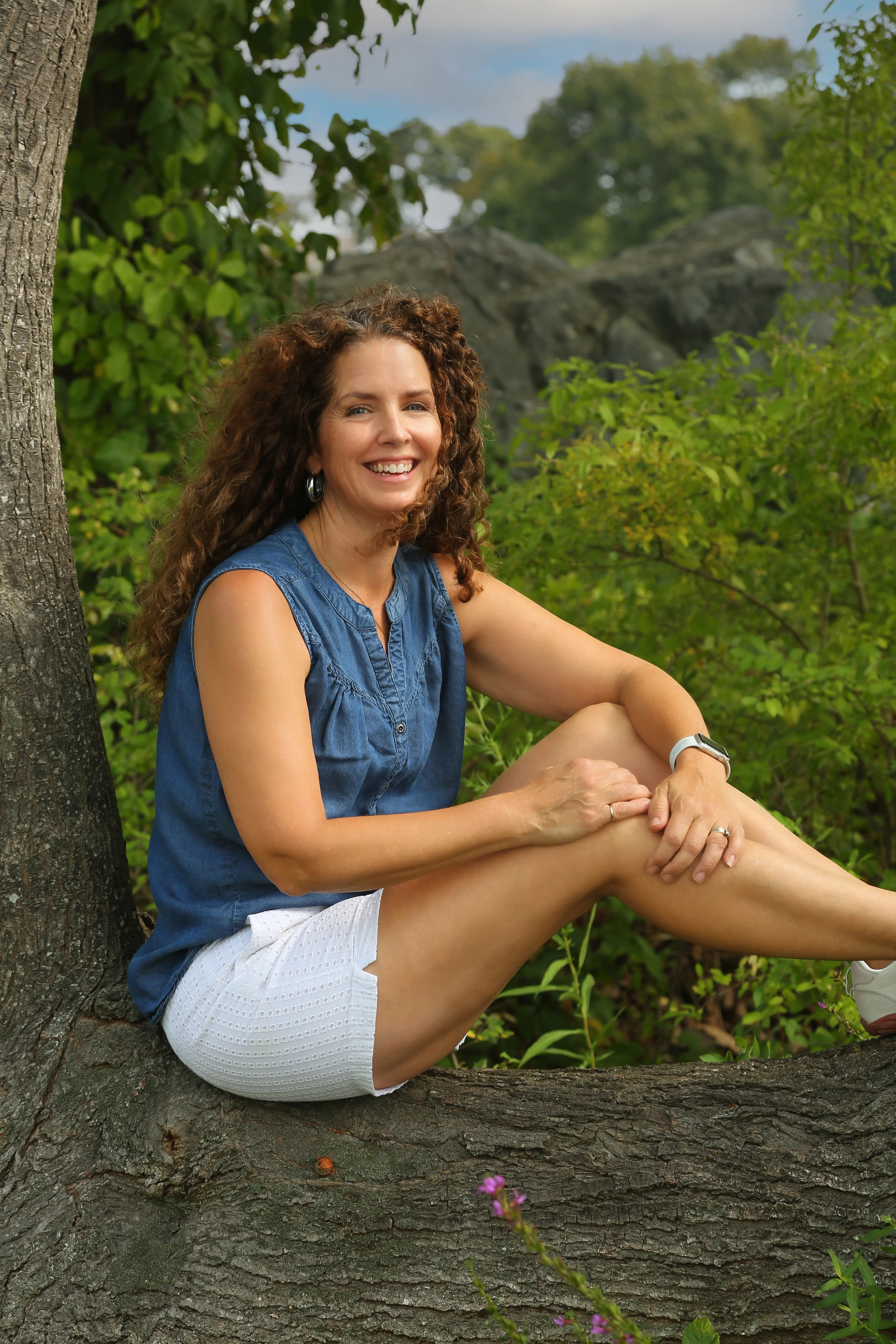 Mother climbing a tree during a playful Westborough family photography session in Central MA.