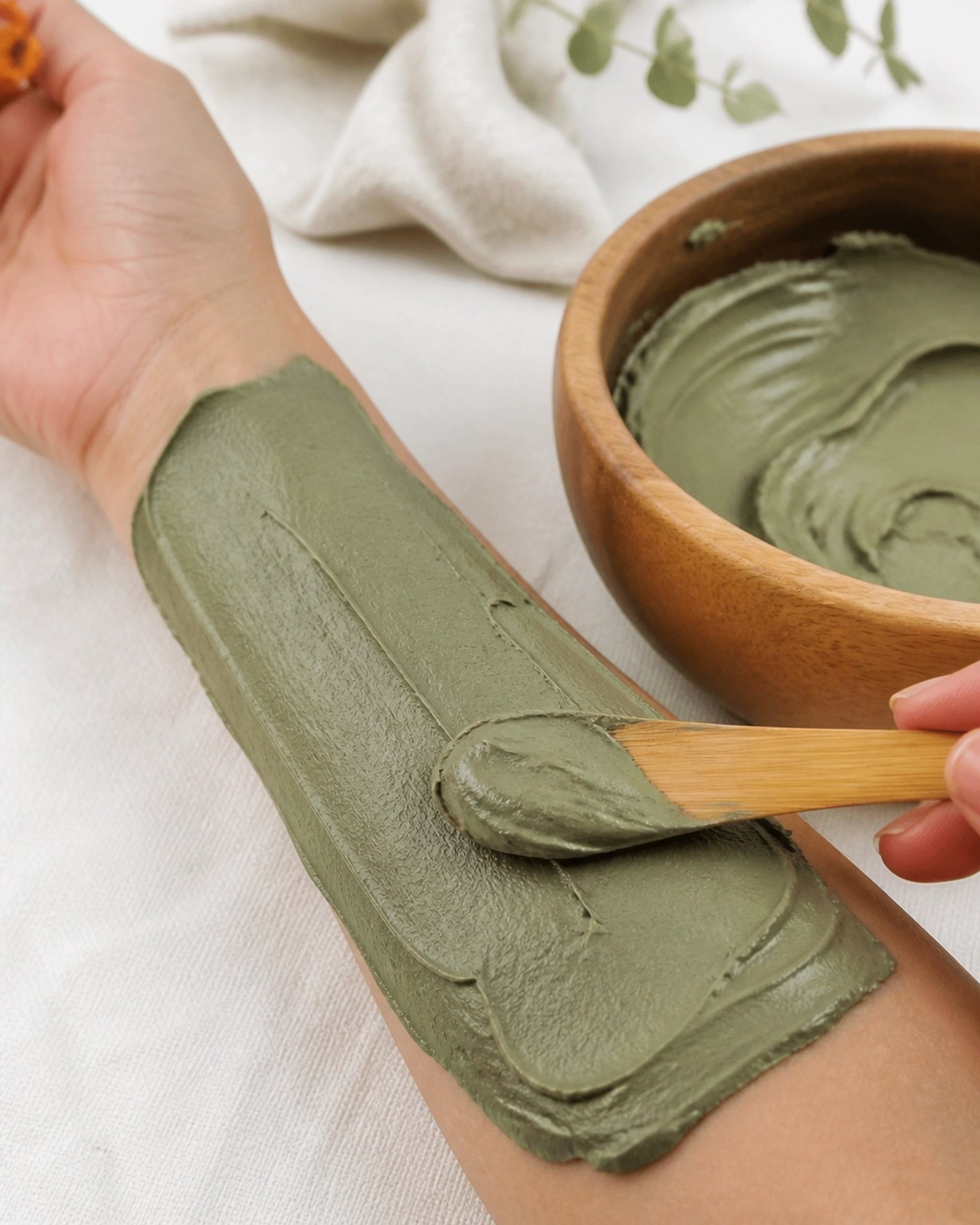 Close up of a green clay poultice being applied to a wrist