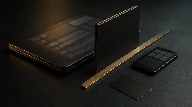 A closed laptop and phone positioned behind a dark notebook and brass ruler, representing protection of creator account permissions