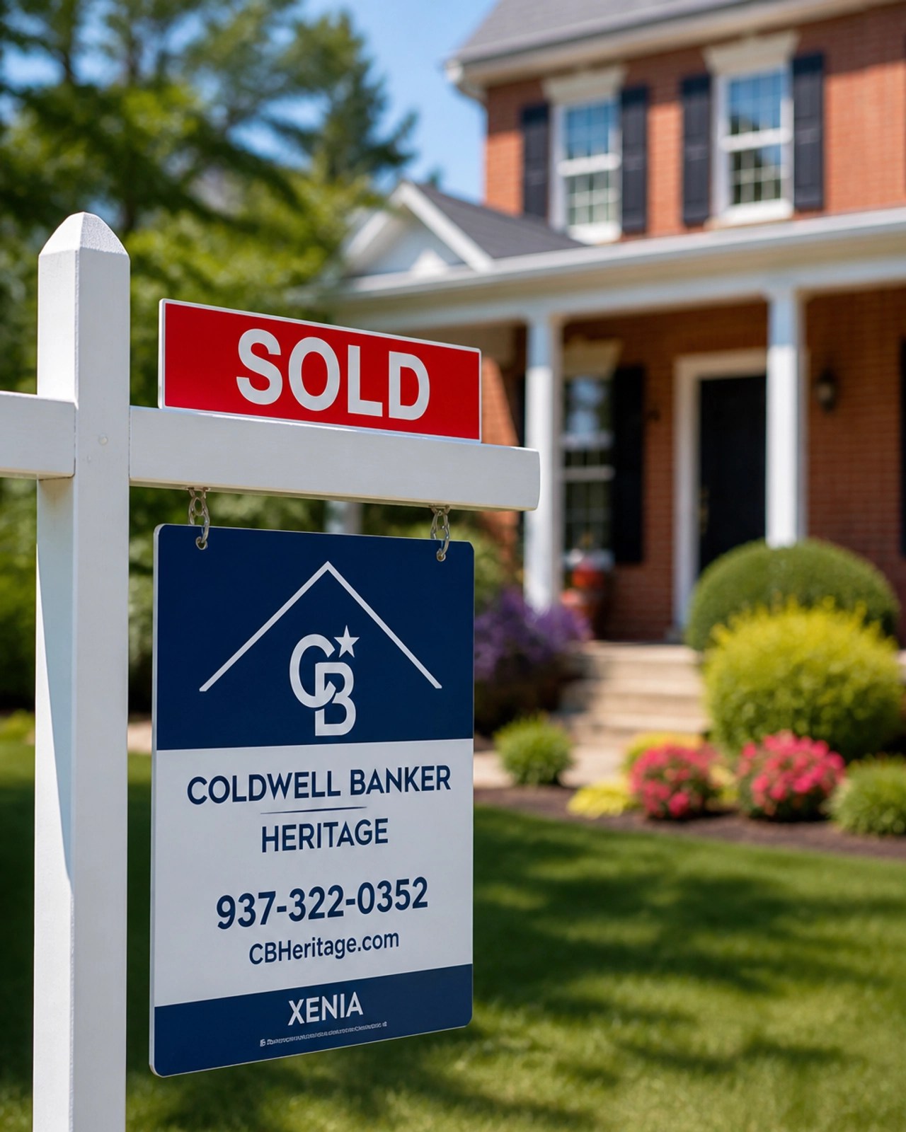 A close-up, professional photograph of a 'Sold' sign in front of a house in Xenia